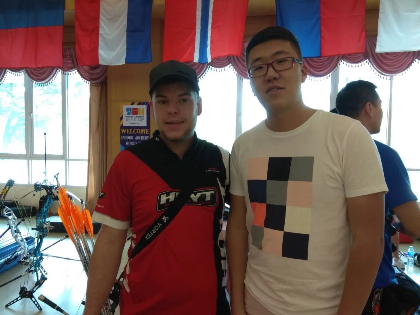 Standing with compound archer Mike Schloesser under the flags at the Bangkok Indoor Archery World Cup, 2017.