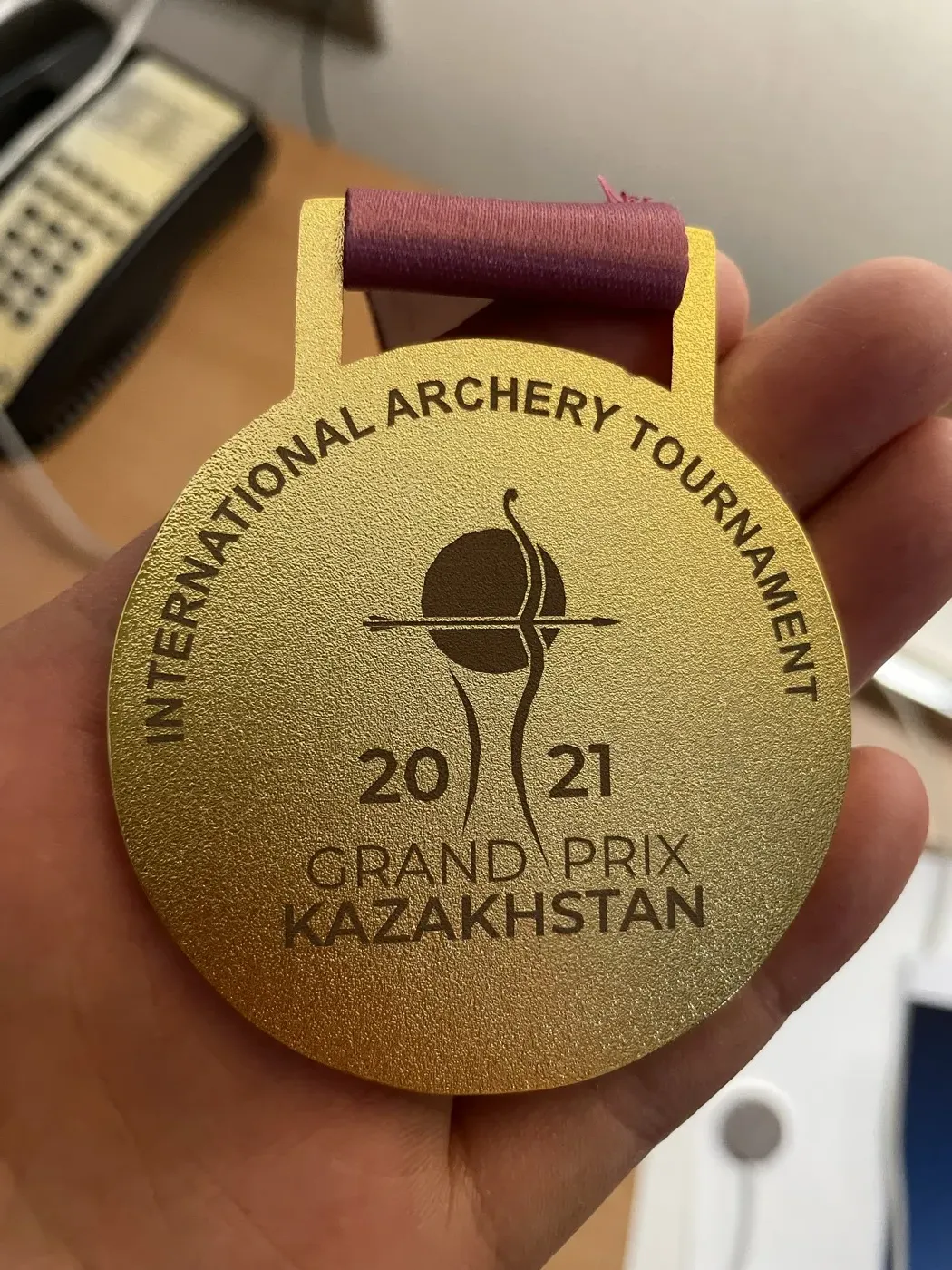 Holding the gold medal from the 2021 Grand Prix Kazakhstan international archery tournament.